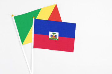 Haiti and Republic Of The Congo stick flags on white background. High quality fabric, miniature national flag. Peaceful global concept.White floor for copy space.
