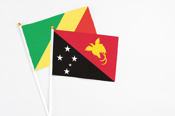 Papua New Guinea and Republic Of The Congo stick flags on white background. High quality fabric, miniature national flag. Peaceful global concept.White floor for copy space.