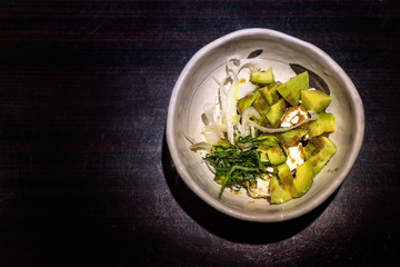 Japanese avocado salad with green sliced vegetables and cream cheese, top view.