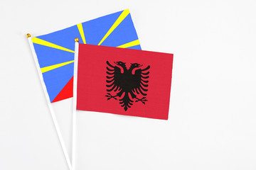 Albania and Reunion stick flags on white background. High quality fabric, miniature national flag. Peaceful global concept.White floor for copy space.