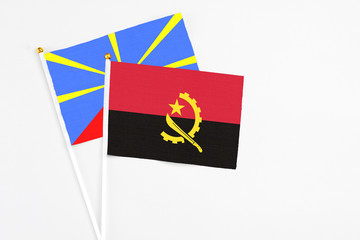 Angola and Reunion stick flags on white background. High quality fabric, miniature national flag. Peaceful global concept.White floor for copy space.