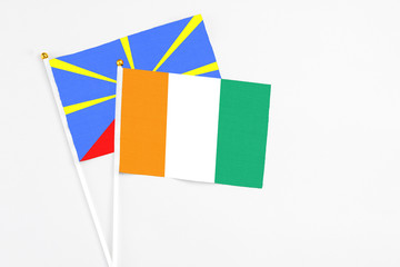 Cote D'Ivoire and Reunion stick flags on white background. High quality fabric, miniature national flag. Peaceful global concept.White floor for copy space.