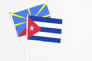 Cuba and Reunion stick flags on white background. High quality fabric, miniature national flag. Peaceful global concept.White floor for copy space.