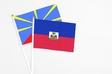 Haiti and Reunion stick flags on white background. High quality fabric, miniature national flag. Peaceful global concept.White floor for copy space.