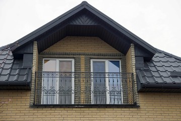 open black iron balcony on the brown brick wall of a private house