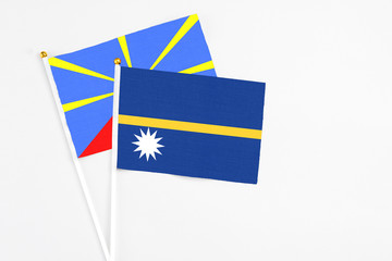 Nauru and Reunion stick flags on white background. High quality fabric, miniature national flag. Peaceful global concept.White floor for copy space.