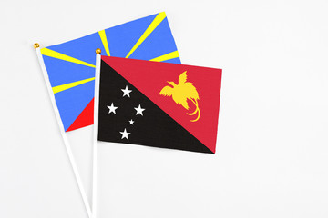 Papua New Guinea and Reunion stick flags on white background. High quality fabric, miniature national flag. Peaceful global concept.White floor for copy space.