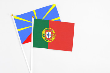 Portugal and Reunion stick flags on white background. High quality fabric, miniature national flag. Peaceful global concept.White floor for copy space.