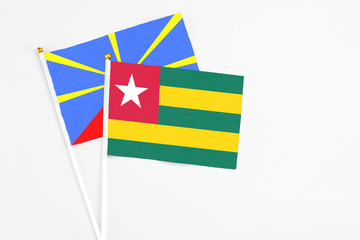 Togo and Reunion stick flags on white background. High quality fabric, miniature national flag. Peaceful global concept.White floor for copy space.