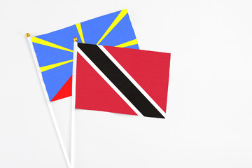 Trinidad And Tobago and Reunion stick flags on white background. High quality fabric, miniature national flag. Peaceful global concept.White floor for copy space.