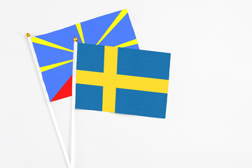 Sweden and Reunion stick flags on white background. High quality fabric, miniature national flag. Peaceful global concept.White floor for copy space.