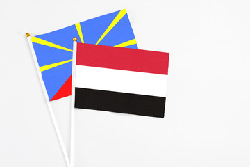 Yemen and Reunion stick flags on white background. High quality fabric, miniature national flag. Peaceful global concept.White floor for copy space.