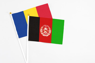 Afghanistan and Romania stick flags on white background. High quality fabric, miniature national flag. Peaceful global concept.White floor for copy space.
