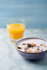 Bowl of granola with yogurt, nuts, raisins, cranberries and chia seeds. Concept for a tasty and healthy meal. Stone - wooden background. Close up.