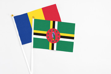 Fototapeta premium Dominica and Romania stick flags on white background. High quality fabric, miniature national flag. Peaceful global concept.White floor for copy space.