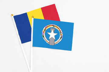 Northern Mariana Islands and Romania stick flags on white background. High quality fabric, miniature national flag. Peaceful global concept.White floor for copy space.