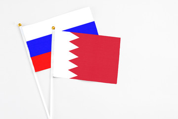 Bahrain and Russia stick flags on white background. High quality fabric, miniature national flag. Peaceful global concept.White floor for copy space.