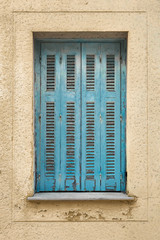 Fototapeta premium Shutters with wall. Ragged wall with closed shutters on the window. Exterior of old shutters and wall. Background of wall with blue vintage shutters. Old vintage retro exterior of the building