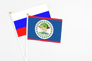 Belize and Russia stick flags on white background. High quality fabric, miniature national flag. Peaceful global concept.White floor for copy space.