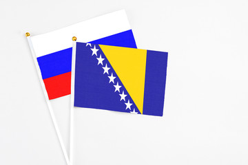 Bosnia Herzegovina and Russia stick flags on white background. High quality fabric, miniature national flag. Peaceful global concept.White floor for copy space.
