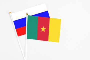 Cameroon and Russia stick flags on white background. High quality fabric, miniature national flag. Peaceful global concept.White floor for copy space.