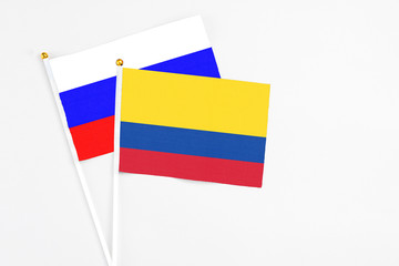 Colombia and Russia stick flags on white background. High quality fabric, miniature national flag. Peaceful global concept.White floor for copy space.
