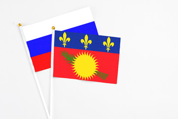 Guadeloupe and Russia stick flags on white background. High quality fabric, miniature national flag. Peaceful global concept.White floor for copy space.