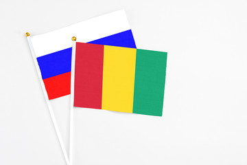 Guinea and Russia stick flags on white background. High quality fabric, miniature national flag. Peaceful global concept.White floor for copy space.