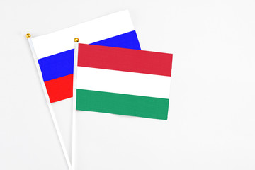 Hungary and Russia stick flags on white background. High quality fabric, miniature national flag. Peaceful global concept.White floor for copy space.