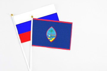 Guam and Russia stick flags on white background. High quality fabric, miniature national flag. Peaceful global concept.White floor for copy space.