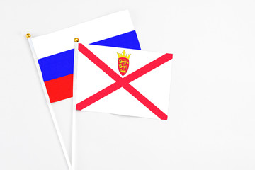 Fototapeta premium Jersey and Russia stick flags on white background. High quality fabric, miniature national flag. Peaceful global concept.White floor for copy space.