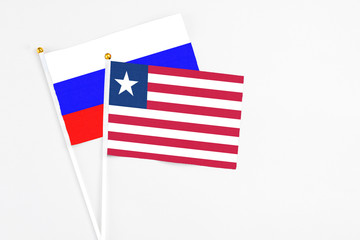 Liberia and Russia stick flags on white background. High quality fabric, miniature national flag. Peaceful global concept.White floor for copy space.