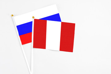 Peru and Russia stick flags on white background. High quality fabric, miniature national flag. Peaceful global concept.White floor for copy space.