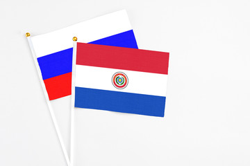 Paraguay and Russia stick flags on white background. High quality fabric, miniature national flag. Peaceful global concept.White floor for copy space.