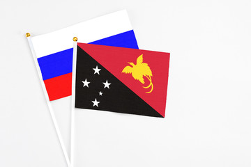 Papua New Guinea and Russia stick flags on white background. High quality fabric, miniature national flag. Peaceful global concept.White floor for copy space.