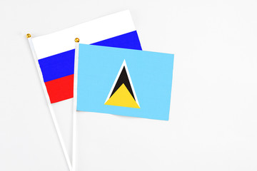 Saint Lucia and Russia stick flags on white background. High quality fabric, miniature national flag. Peaceful global concept.White floor for copy space.