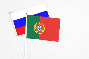 Portugal and Russia stick flags on white background. High quality fabric, miniature national flag. Peaceful global concept.White floor for copy space.