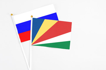 Seychelles and Russia stick flags on white background. High quality fabric, miniature national flag. Peaceful global concept.White floor for copy space.