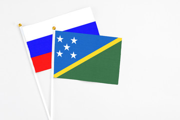 Solomon Islands and Russia stick flags on white background. High quality fabric, miniature national flag. Peaceful global concept.White floor for copy space.