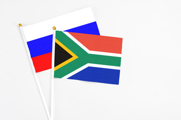 South Africa and Russia stick flags on white background. High quality fabric, miniature national flag. Peaceful global concept.White floor for copy space.