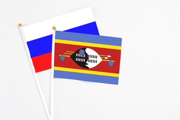 Swaziland and Russia stick flags on white background. High quality fabric, miniature national flag. Peaceful global concept.White floor for copy space.