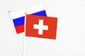 Switzerland and Russia stick flags on white background. High quality fabric, miniature national flag. Peaceful global concept.White floor for copy space.