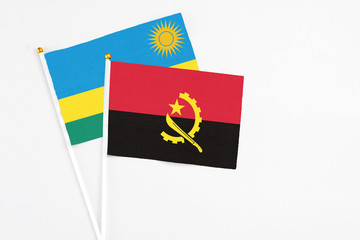 Angola and Rwanda stick flags on white background. High quality fabric, miniature national flag. Peaceful global concept.White floor for copy space.