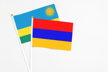 Armenia and Rwanda stick flags on white background. High quality fabric, miniature national flag. Peaceful global concept.White floor for copy space.