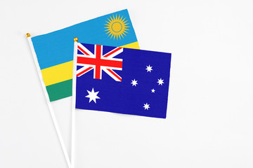 Fototapeta premium Australia and Rwanda stick flags on white background. High quality fabric, miniature national flag. Peaceful global concept.White floor for copy space.