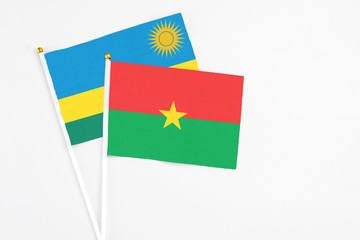 Burkina Faso and Rwanda stick flags on white background. High quality fabric, miniature national flag. Peaceful global concept.White floor for copy space.