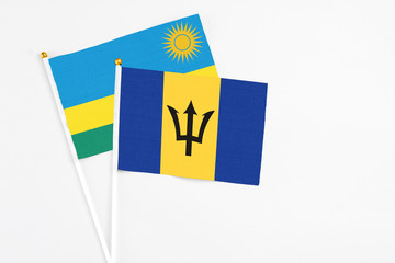 Barbados and Rwanda stick flags on white background. High quality fabric, miniature national flag. Peaceful global concept.White floor for copy space.