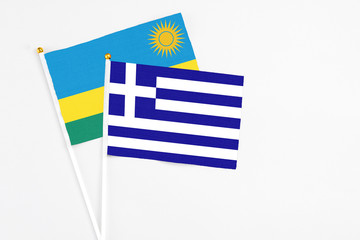 Obraz premium Greece and Rwanda stick flags on white background. High quality fabric, miniature national flag. Peaceful global concept.White floor for copy space.