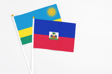 Haiti and Rwanda stick flags on white background. High quality fabric, miniature national flag. Peaceful global concept.White floor for copy space.