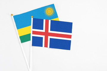 Fototapeta premium Iceland and Rwanda stick flags on white background. High quality fabric, miniature national flag. Peaceful global concept.White floor for copy space.